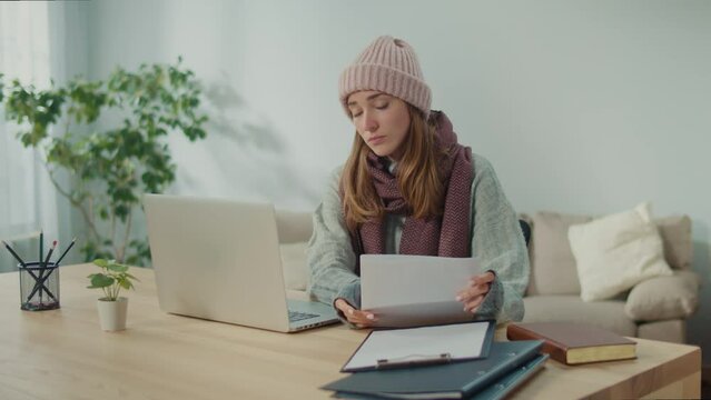 Unhappy Woman in Warm Clothes Sit at Workplace Holding Papers Reading Bad News in Letter Feels Frustrated, Concerned Due High Taxes, Loan Debt, Dismissal, Staff Cuts Notice, Debt Eviction Notification