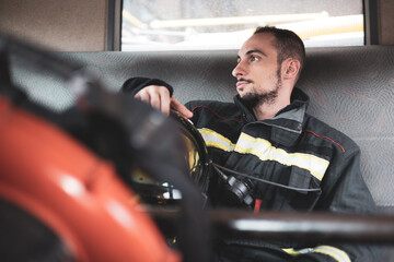 A firefighter sitting in the back of a truck, the man is thoughtful because he has not been...