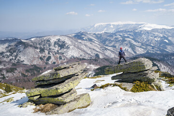Mountain hiker standing on the cliff, looking at the impressive, distant snowcapped mountains - 549315115