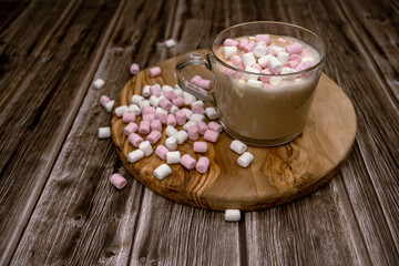 Coffee in a glass on a wooden table with mini marshmallow