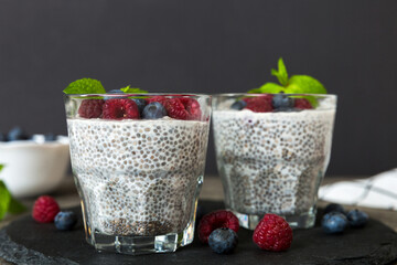 Healthy breakfast or morning with chia seeds vanilla pudding raspberry and blueberry berries on table background, vegetarian food, diet and health concept. Chia pudding with raspberry and blueberry