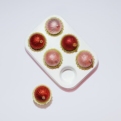 Christmas baubles in a baking mold. Creative winter holidays inspired layout, traditional baking idea. Cupcakes or muffins. 