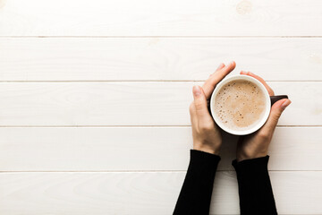 Minimalistic style woman hand holding a cup of coffee on Colored background. Flat lay, top view...