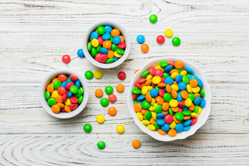 different colored round candy in bowl and jars. Top view of large variety sweets and candies with...
