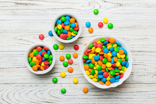 different colored round candy in bowl and jars. Top view of large variety sweets and candies with copy space