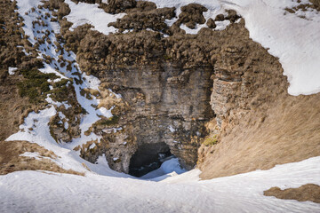 Amazing, steep, snow covered entrance to the cave called Ponor with a frozen waterfall inside - 549319393