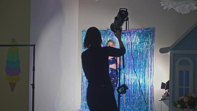 blonde model woman in a sequin blue dress on the background of New Year sequins rain, photo shoot at the photographer studio on Christmas day
