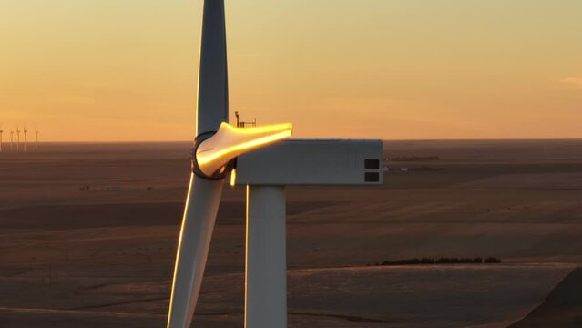 Wind turbine at sunset with golden glow (Aerial drone footage close-up)