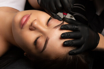 Beauty master making permanent makeup with a machine