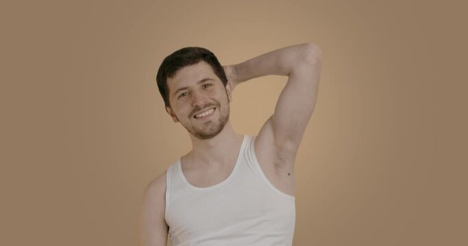Handsome Caucasian man looking in mirror, applying underarm deodorant to armpit, preventing sweat. Happy young man using antiperspirant after morning shower, enjoying daily skin care routine.