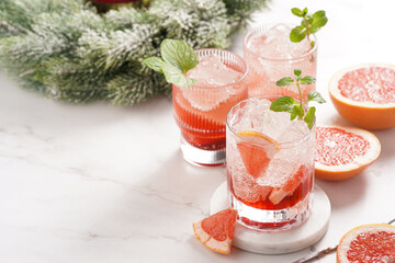 Preparation of a grapefruit alcohol free cocktail - several tumbler glasses with ice cubes on...
