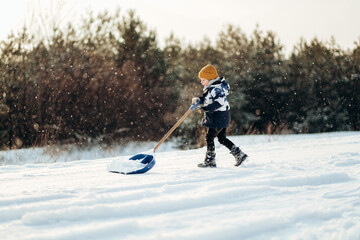 Little boy with big shovel to clear snow