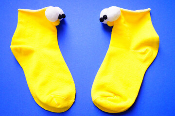 Two bright blue socks with funny eyes on a blue background. Puppet theatre. View from above.