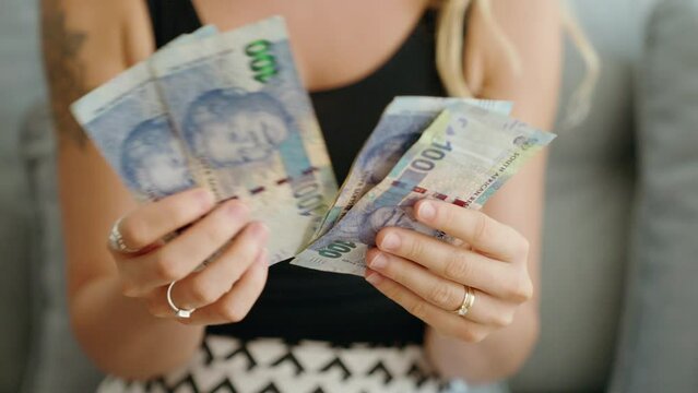 Young woman counting south africa 100 rand banknotes at home