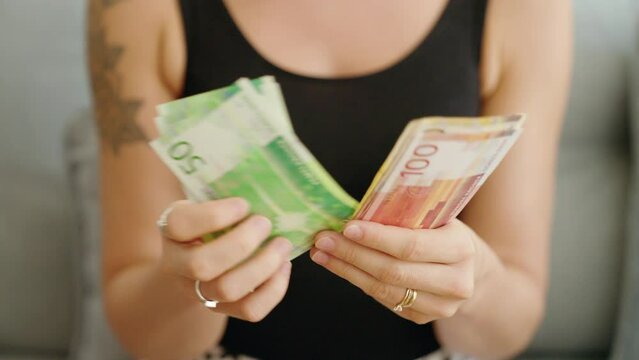 Young woman counting norway krone banknotes at home