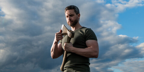 man with axe. caucasian woodsman man hold ax. brutal man on dramatic sky background