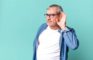 middle age senior man looking serious and curious, listening, trying to hear a secret conversation...