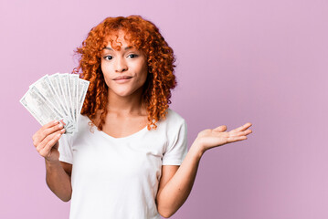 red hair pretty woman feeling puzzled and confused and doubting. dollar banknotes and money concept