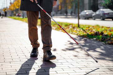 Blind person close-up with a walking stick. Walking down the street