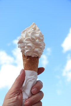 Hand holding waffle cone with twisted ice cream