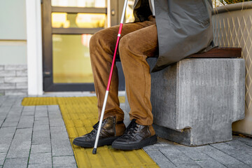 Tactile tiles in the city. Close-up of a blind man with a cane