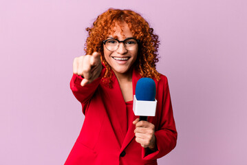 red hair pretty woman pointing at camera choosing you. journalist and presenter concept