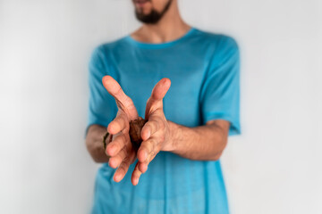 The man holds a wooden massager in hands