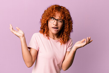 redhair pretty woman shrugging with a dumb, crazy, confused, puzzled expression, feeling annoyed...