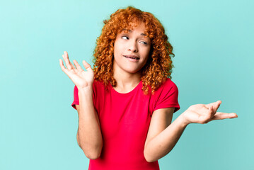 redhair pretty woman shrugging with a dumb, crazy, confused, puzzled expression, feeling annoyed...