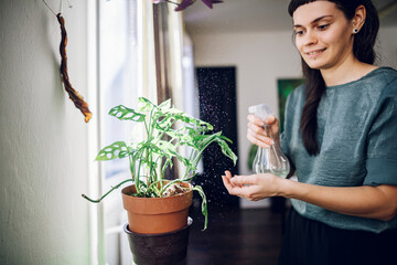 Fashionable young woman taking care of her house plants