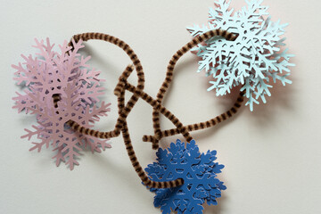 collection of blue and pink paper snowflakes strung on pipe cleaners