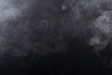 Dense Fluffy Puffs of White Smoke and Fog on black Background, Abstract Smoke Clouds, Movement Blurred out of focus. Smoking blows from machine dry ice fly fluttering in Air, effect texture