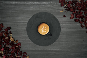 Gray wooden background with round stone plate, coffee cup and red dry leaves
