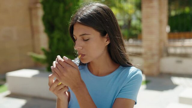Young beautiful hispanic woman smoking at street