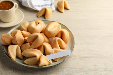 Tasty fortune cookies and paper with prediction on wooden table, space for text