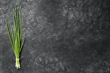 Bunch of fresh green onion on black table, top view. Space for text - obrazy, fototapety, plakaty
