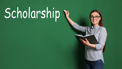 Scholarship concept. Happy student with book and chalk on green background