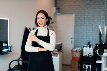 Portrait of a young asian female hairdresser holding qualified haircut tools in her salon for a...