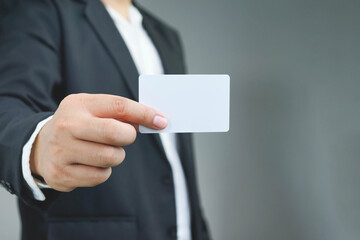 Businessman ,Business Man's hand hold showing business card - close grey background. shows business card with copy space, Show a blank piece of card.