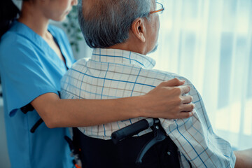 Rear view of a caregiver and her contented senior patient gazing out through the window. Elderly...