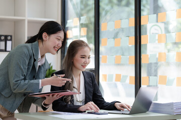 Female business worker with colleagues in Thailand working together at office desk, Female office worker business suit working with document file and paper work.