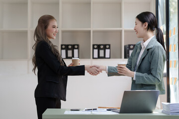 Female business worker with colleagues in Thailand working together at office desk, getting shaking hands, successful and agreement concept