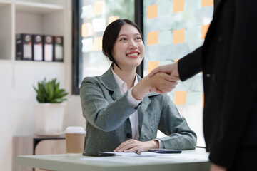 Female business worker with colleagues in Thailand working together at office desk, getting shaking hands, successful and agreement concept