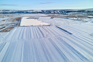 Aerial view of snow covered agricultural fields with barren surface in winter