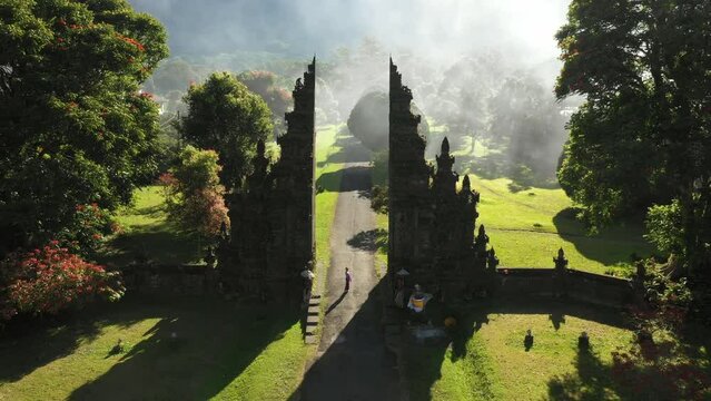 Aerial view of balinese woman with traditional dress standing at temple gate, Bali, Indonesia