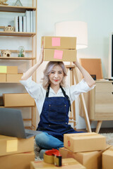 Starting small business entrepreneur of independent Asian woman smiling using computer laptop with cheerful success of online marketing package box items and SME delivery concept