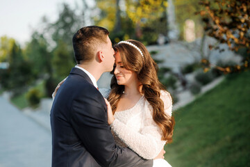 A wedding couple poses in a park near a building