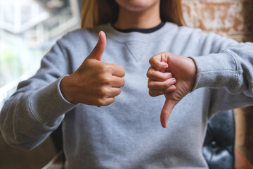 Closeup image of a woman making thumbs up and thumbs down hands sign
