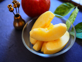 テーブルに置かれたう器に盛ったカット林檎と丸い林檎