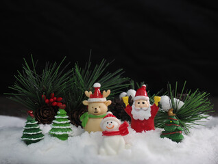 Santa Clause and friends sitting on white snow  with blurred Christmas trees on black background to created greeting card , Happiness and funny Christmas and  New Year concept